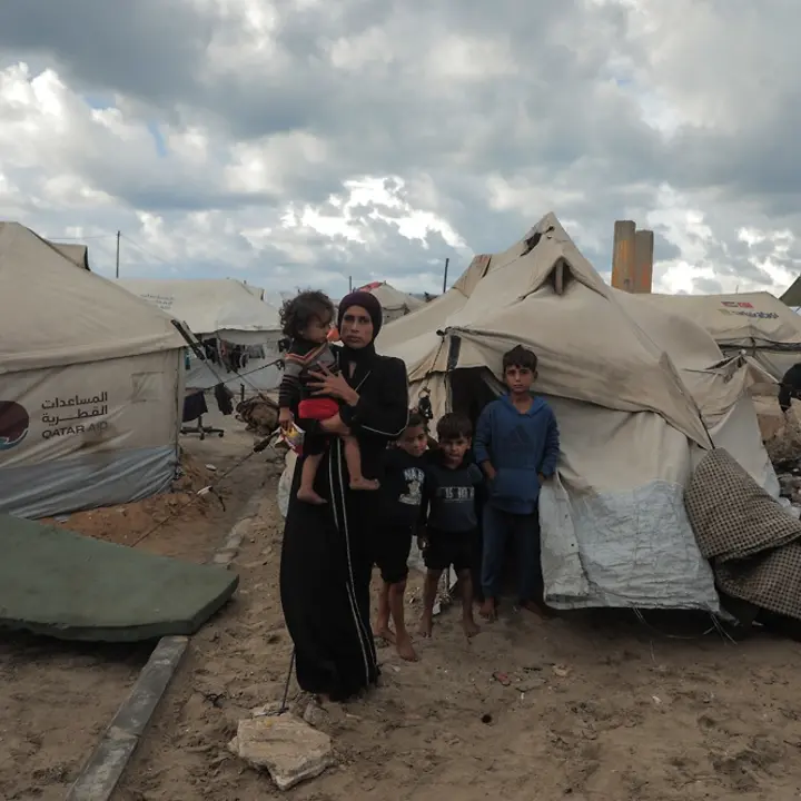 Maysaa steht mit ihren Kindern vor einem provisorischen Zelt