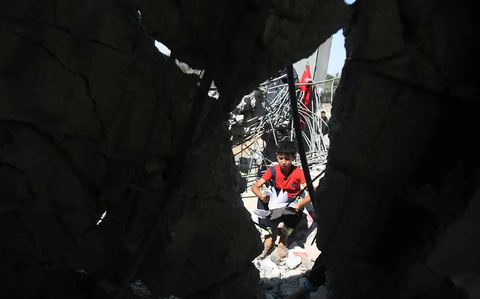 Mit seinem Schulbesuch in der Hand sitzt dieser Junge inmitten der Zerstörung in der Stadt Khan Yunis im Gazastreifen. | ©UNICEF/El Baba Palästina: Kinder schützen im Gazastreifen
