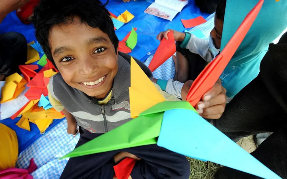 Ein Junge freut sich über den gebastelten Papierflieger | © UNICEF/Karki Erdbeben Nepal: Junge mit Papierflieger